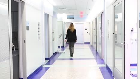 Nurses-and-doctors-walking-down-the-white-hall-of-a-hospital-and-into-patients-rooms-b-roll