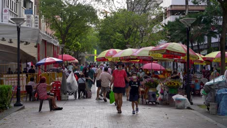 People-walking-at-Waterloo-Street-downtown-SIngapore,-Stalls-selling-flowers-near-the-temple