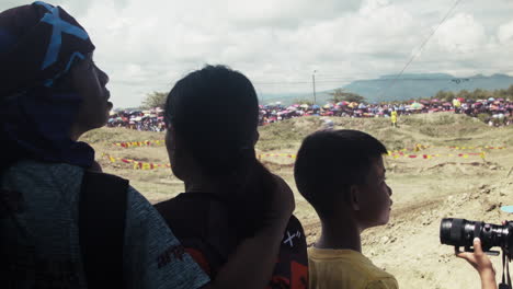 A-family-of-onlookers-watch-in-awe-as-multiple-dirt-bikes-speed-thru-up-close-at-the-motocross-competition