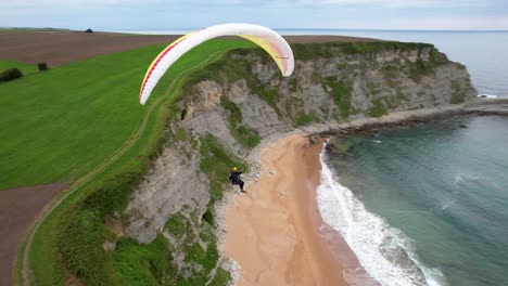 Person-Beim-Gleitschirmfliegen-über-Einer-Wunderschönen-Küste-In-Spanien---Luftaufnahme