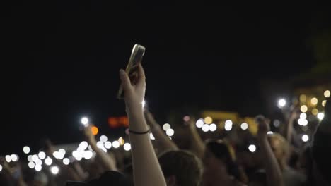 People-In-The-Audience-Waving-Hands-Holding-Smartphones-With-Flashlights-On