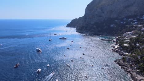 Aerial-drone-shot-of-boats,-yachts-on-the-coastline-of-Capri,Italy