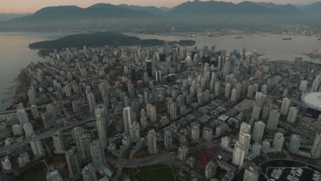 Aerial-wide-shot-of-Downtown-Vancouver-revealing-mountains,-Dusk