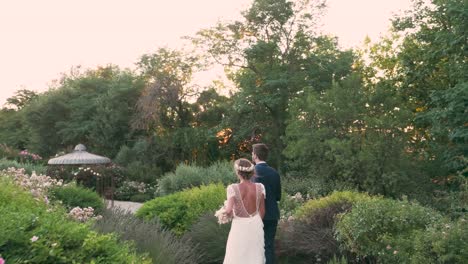 Die-Kamera-Folgt-Bräutigam-Und-Braut-Am-Hochzeitstag-Im-Wunderschönen-Garten