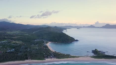 Aerial-wide-view-of-Nacpan-Beach-and-Twin-Beach-at-sunset-on-Palawan,-the-Philippines-camera-slightly-tracking-backwards-tilting-down