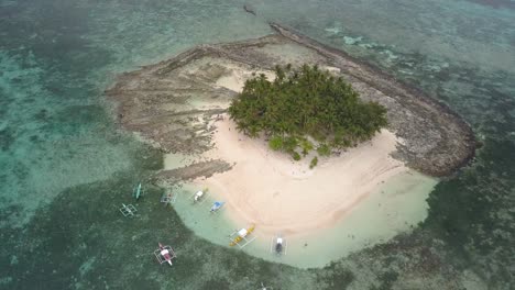 Aerial-pedestal-down-tilting-up-shot-of-sandy-Guyam-Island,-Siargao,-the-Philippines