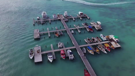 Dos-Personas-Caminan-Por-El-Muelle-Hacia-Los-Barcos-Sentados-En-El-Mar-Caribe-Azul-En-Aruba