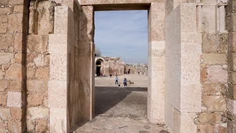 Ruinas-Antiguas-De-Muro-De-Piedra-Con-Entrada-Conservada-Con-Un-Edificio-De-Arquitectura-Islámica-En-El-Fondo