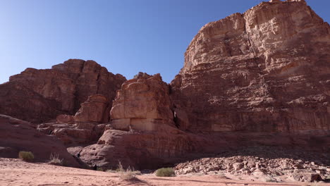 Tourists-Climbing-on-the-Massive-Red-Rock-Mountain-in-the-Middle-of-Wadi-Rum-Desert-on-a-Bright-and-Sunny-Day