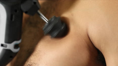 Athlete-using-a-percussive-therapy-gun-on-chest-for-releif,-recover-and-muscle-activation