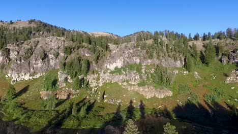 Zooming-panorama-of-a-mountain-lake-then-flying-towards-the-dark-forest