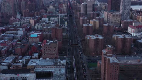 Short-backward-drone-flight-over-elevated-train-tracks-of-Harlem,-New-York-City-just-after-sunrise