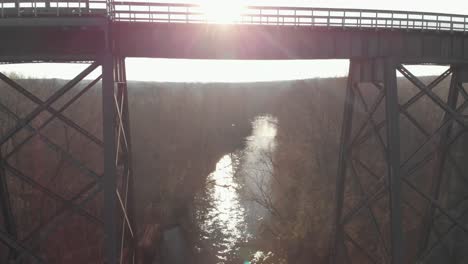 Slowly-rising-above-the-Appomattox-River-reflecting-afternoon-sunlight-to-reveal-High-Bridge-Trail,-a-reconstructed-Civil-War-railroad-bridge