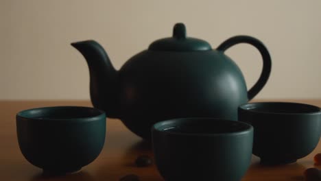Minimaler-Hintergrund-Eines-Grünen-Japanischen-Teesets-Mit-Dampf-Aus-Den-Tassen,-Auf-Einem-Holztisch,-Mit-Einigen-Steinen-Herum