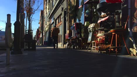 Pedestrian-walking-by-a-thrift-store-in-Toronto-as-late-afternoon-sun-takes-hold