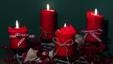 Modern-Christmas-wreath-with-four-red-candles-on-wooden-surface-with-green-background,-holiday-interior-design