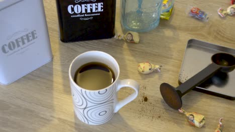 Auf-Dem-Tisch-Steht-Eine-Tasse-Heißen-Schwarzen-Kaffee-Mit-Süßigkeiten-Und-Metallischen-Kaffeeschachteln