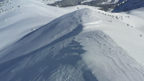 Aerial-view-flying-along-a-snow-covered-mountain-ridge,-to-then-reveal-the-Megeve-and-Chamonix-valleys-in-the-distance