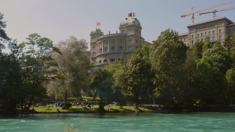 wide-low-angle-shot-on-the-Bundeshaus-in-Bern,-Switzerland-from-the-Aare-river-site-on-a-windy-day-ZOOM-IN