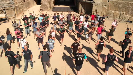 Drone-shot-flying-backwards-over-pipes-and-drums-musicians-marching-in-the-roman-arena-in-Avenches-Switzerland