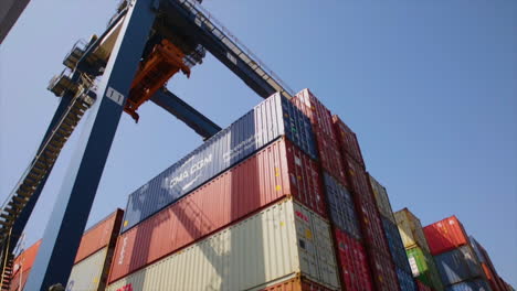 A-konecrane-is-moving-over-the-hundreds-of-containers-at-the-port,-low-angle-view