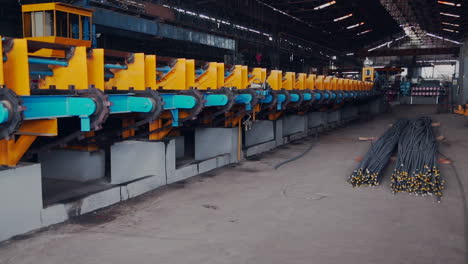 An-iron-factory-panning-view,-A-bunch-of-a-steel-bars-on-the-ground-and-a-row-of-machines,-perspective-view