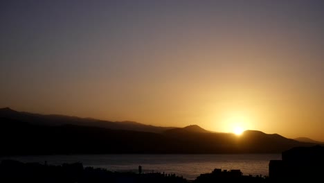 sun-setting-behind-mountains-above-bay-timelapse