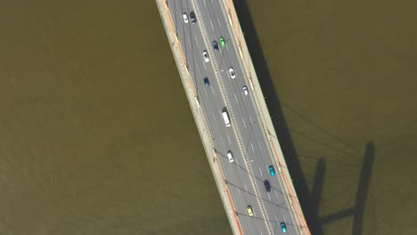 Car-traffic-on-hanging-sea-bridge-over-bay-in-city-view-from-above