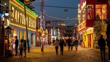 Menschen-Genießen-Die-Sehenswürdigkeiten-Und-Geräusche-Eines-Vergnügungsparks-Im-Prater-Bei-Nacht-Mit-Fahrgeschäften-Und-Abendhimmel-Im-Hintergrund---Zeitrafferaufnahme-4k