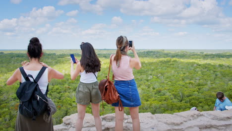 Wide-shot-of-people-enjoying-the-view-on-top-of-mayan-pyramid-at-Muyil-archeological-site,-Chunyaxche,-Quintana-Roo,-Mexico