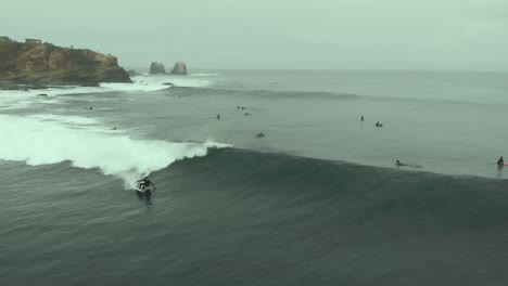 Aerial-shot-following-Surfer-riding-Wave-and-falling-on-a-cold-day-at-Pichilemu,-Chile