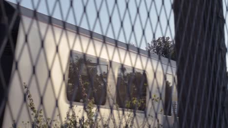 POV-of-train-carriages-passing-by-slowly-through-view-of-railway-fencing