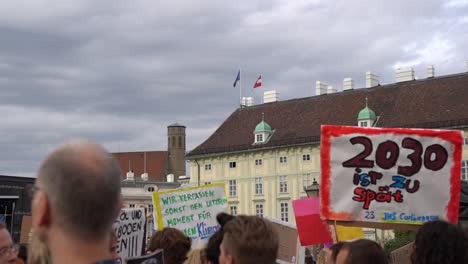 Vista-De-La-Multitud-Sosteniendo-Carteles-Con-El-Telón-De-Fondo-De-La-Bandera-Austriaca-Y-Europea-Durante-Los-Viernes-Para-Futuras-Protestas-Por-El-Cambio-Climático-A-Cámara-Lenta