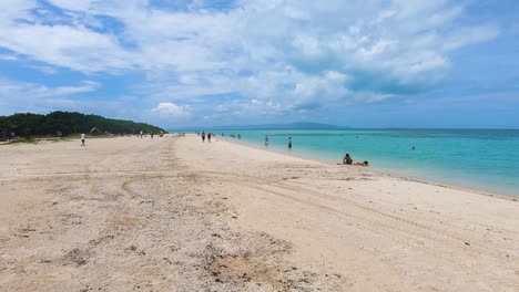 Toma-Estacionaria-De-Turistas-Japoneses-Disfrutando-De-La-Serena-Playa-De-Kondoi,-Isla-De-Taketomi,-Okinawa,-Japón