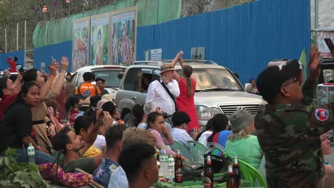 Toma-Exterior-Mediana-De-Turistas-Mirando-Hacia-Arriba-Y-Filmando-Con-Sus-Teléfonos-Mientras-Otros-Están-Sentados-Con-Un-Refrigerio-Mientras-El-Tráfico-Se-Mueve-Lentamente-Frente-A-Ellos