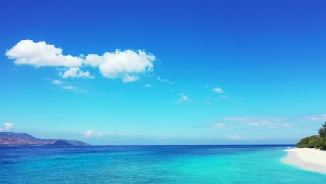 Wunderschöner-Strahlend-Blauer-Himmel-Mit-Weißen-Wolken,-Die-über-Dem-Ruhigen-Blauen-Azurblauen-Meer-Und-Dem-Weißen-Sandstrand-Tropischer-Inseln-Auf-Bali-Hängen