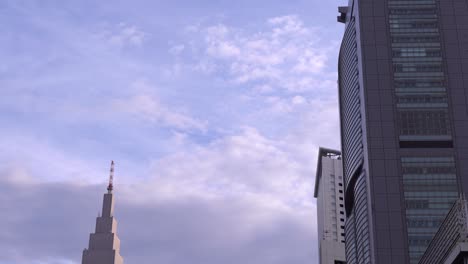 Airplane-Flying-Over-The-Skyline-Tower-Of-Docomo-Yoyogi-Building-In-Shinjuku-Tokyo-Japan---Low-Angle-Shot