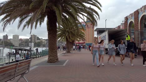 Walking-towards-Luna-Park-main-face-entrance-in-the-northern-shore-on-an-overcast-day-with-people-walking-along,-Stable-walking-handheld-shot