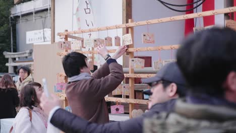 Mann-Fotografiert-Ein-Kleines-Holzschild-Beim-Neujahrsfest-Am-Yasaka-Schrein-In-Kyoto,-Japan