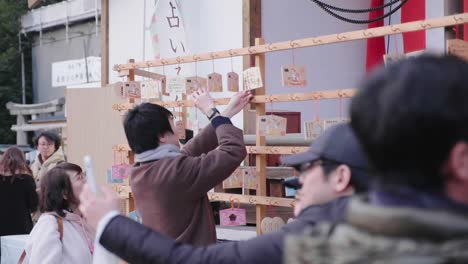 Guy-taking-photo-of-little-wooden-sign-at-New-Year-day-festival-at-Yasaka-Shrine-in-Kyoto,-Japan