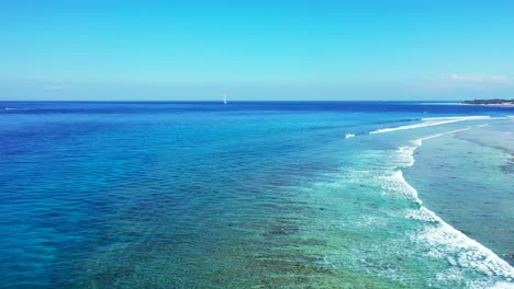 Peaceful-seascape-with-ocean-waves-foaming-over-calm-turquoise-lagoon-with-rocky-seabed-under-bright-blue-sky,-Caribbean