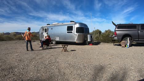 Three-people-conversing-in-front-of-Airstream-trailer-and-truck