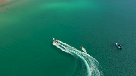 Luftdrohnenfoto-Eines-Extremen-Motorboot-Donut-Wassersports,-Der-Mit-Hoher-Geschwindigkeit-In-Der-Tropischen-Türkisfarbenen-Bucht-Kreuzt