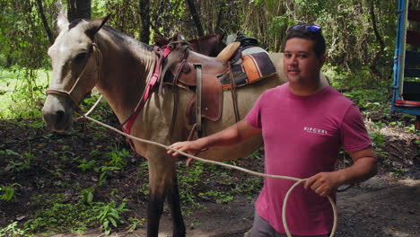 Cámara-Lenta-De-Un-Joven-Sonriente-Preparándose-Para-Montar-A-Caballo-En-Nosara,-Costa-Rica