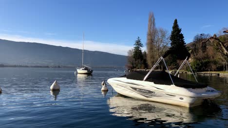 Static-shot-of-Larson-boat-in-the-water,-covered-and-rocking-in-the-small-waves-of-Lake-Leman