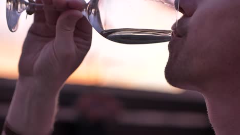 Man-drinking-glass-of-white-wine,-sampling-aroma,-taste-at-testing-celebration-event-at-sunset