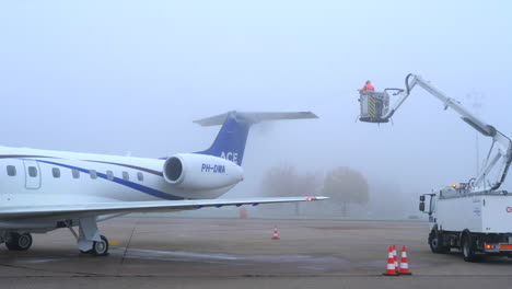 An-aircraft-undergoing-deicing-at-an-airport-apron-on-a-misty,-winter-day