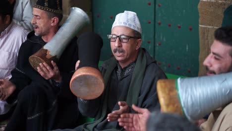 High-angle-closeup-of-men-in-traditional-clothing-chanting-and-hitting-drums-going-into-a-trance-during-a-Sufi-ceremony