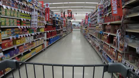 POV-from-the-shopping-cart-while-going-down-the-coffee,-tea-and-baking-supply-aisle-at-the-grocery-store