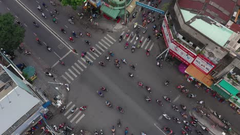 Toma-De-Un-Dron-De-ángulo-Alto-De-Arriba-Hacia-Abajo-De-Una-Concurrida-Intersección-Observando-El-Caos-Organizado-Del-Tráfico-De-Motocicletas-De-Saigón